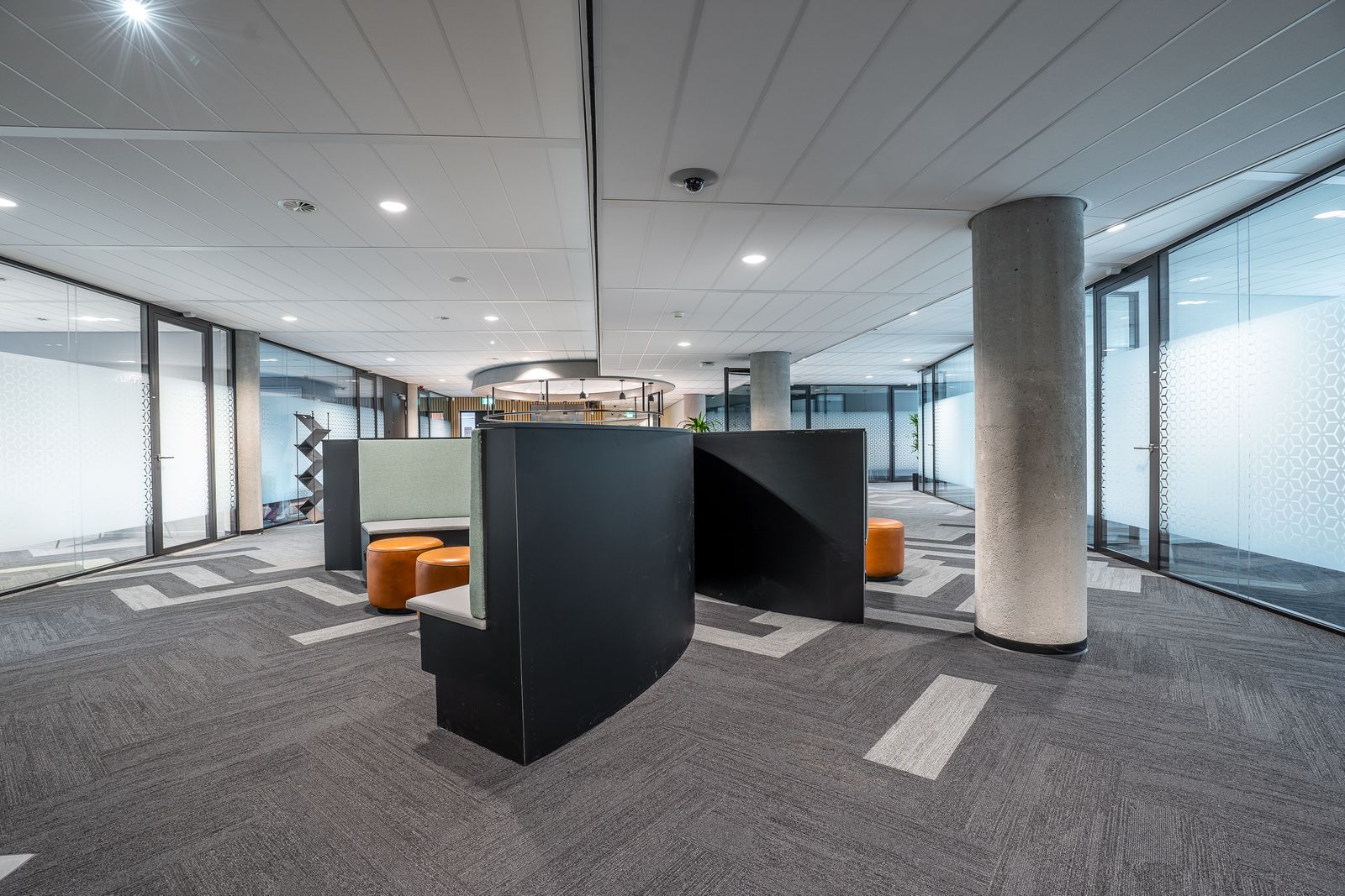 Finished commercial office fit-out with glass partitions and breakout seating