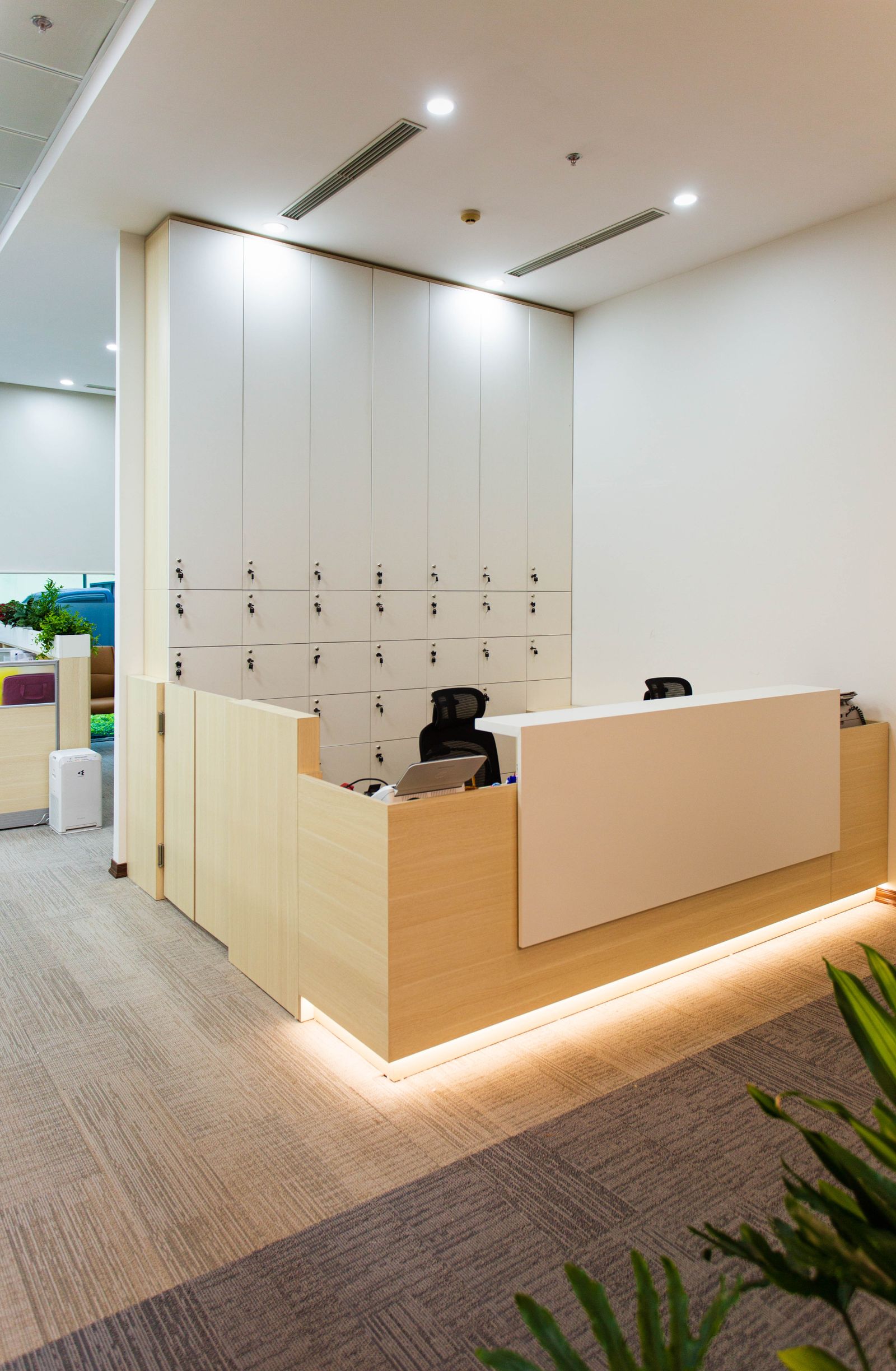 Office reception desk with staff lockers and feature lighting