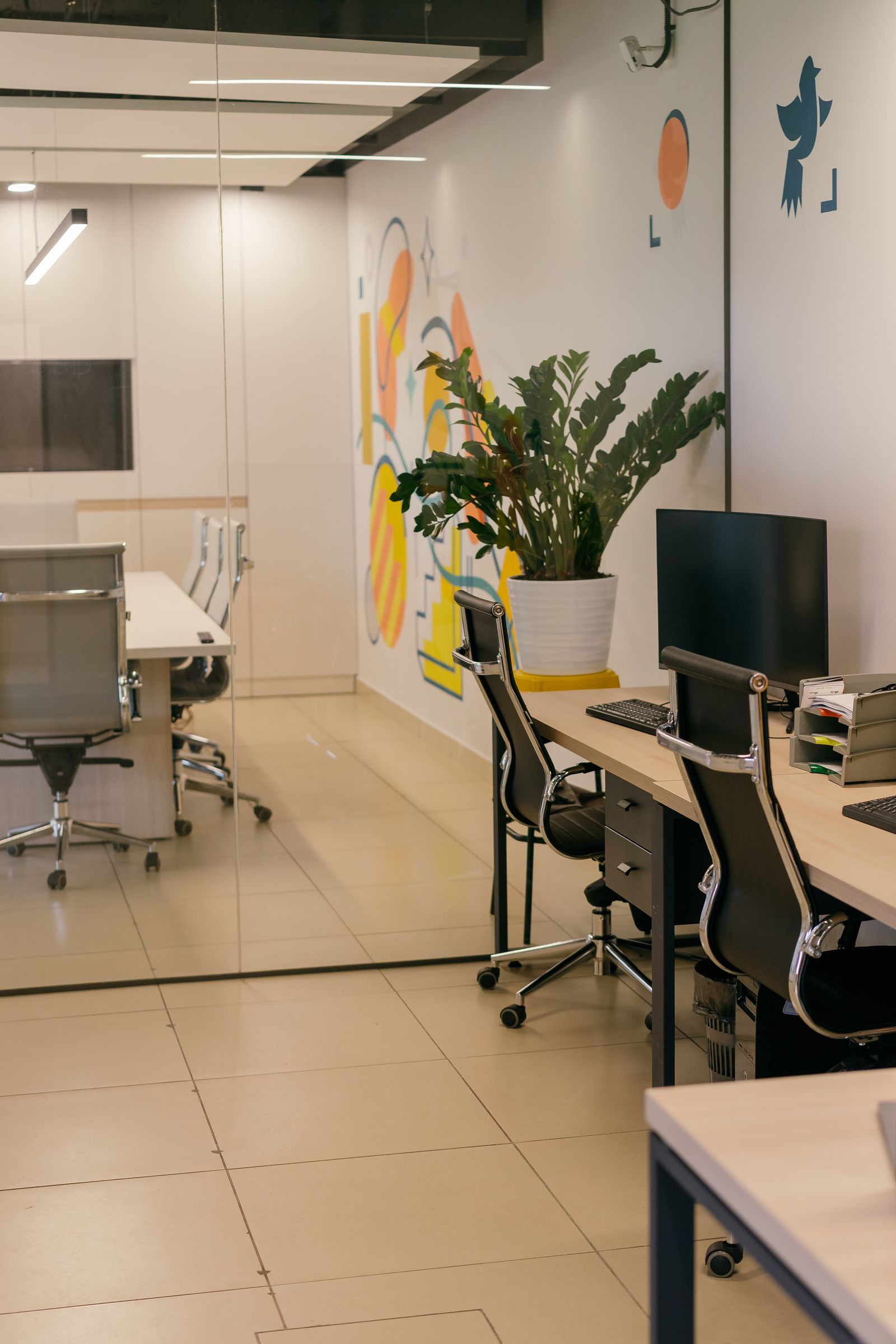 Open-plan workspace with wall mural and glass meeting room