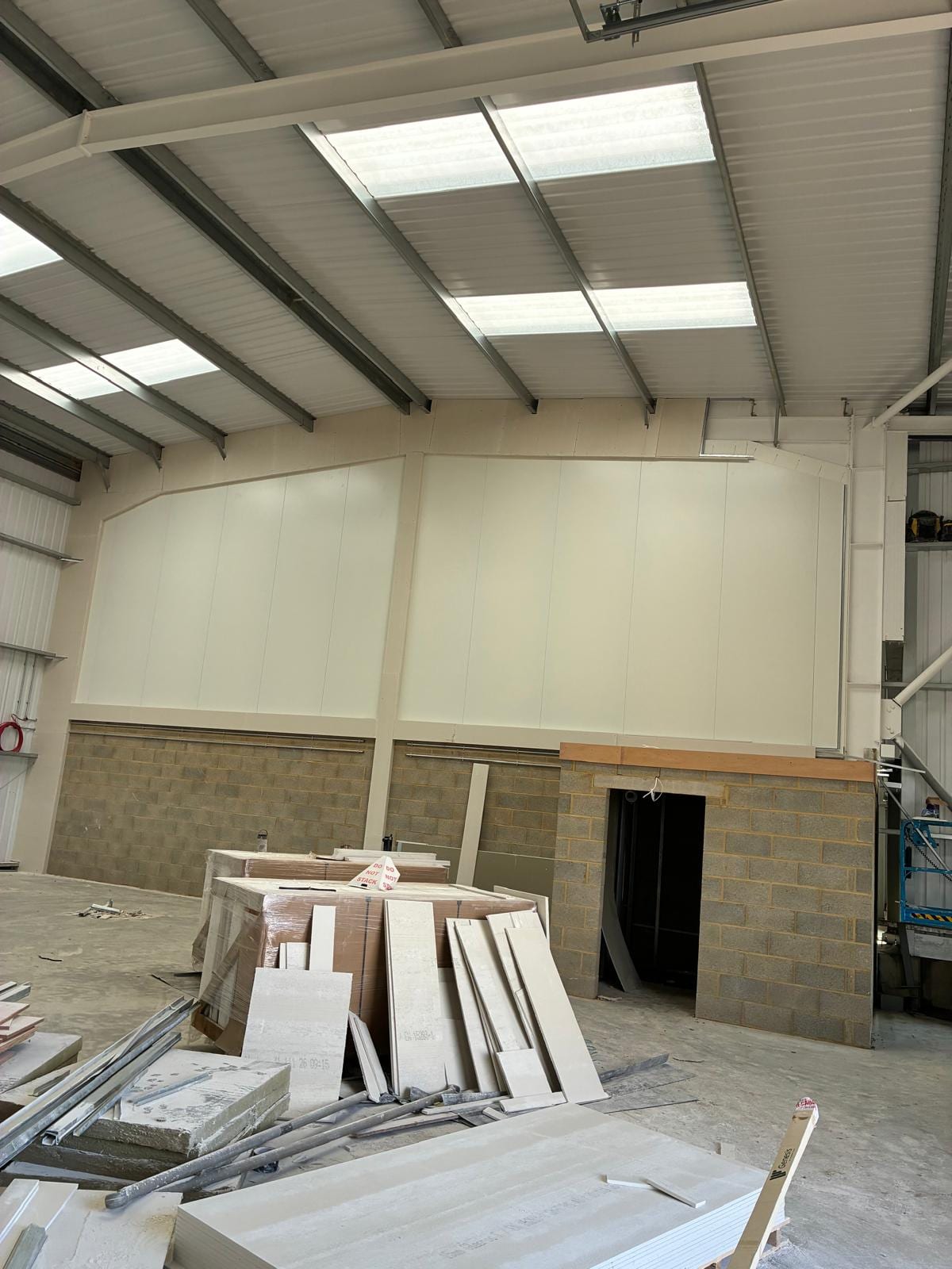 Wall lining panels going up in the warehouse unit with boards stacked below
