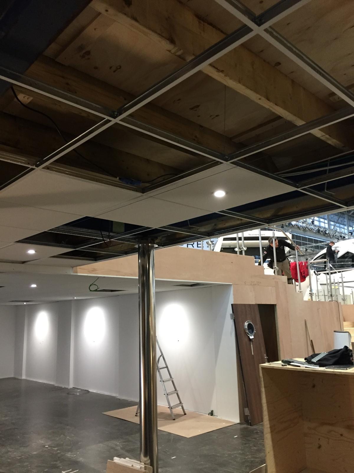 Partitions and ceiling grid going in with the exhibition hall visible beyond