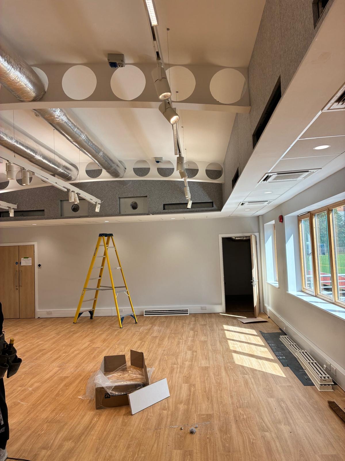 Long hall with the acoustic ceiling installed above a timber floor and windows down one side