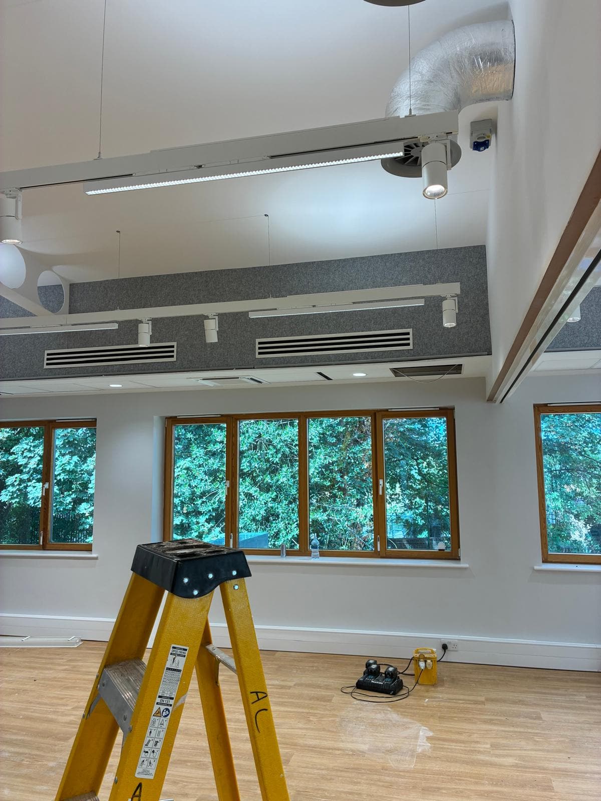 Acoustic ceiling rafts and ventilation grilles above timber framed windows