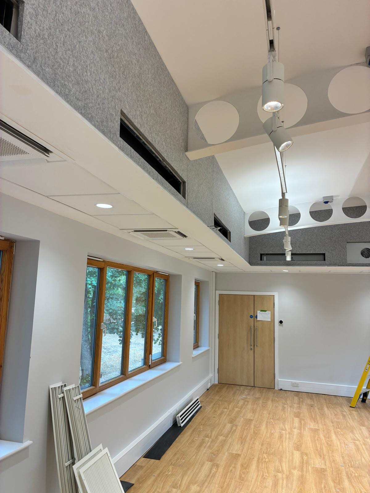 Acoustic ceiling and downlights running the length of the hall towards a timber door