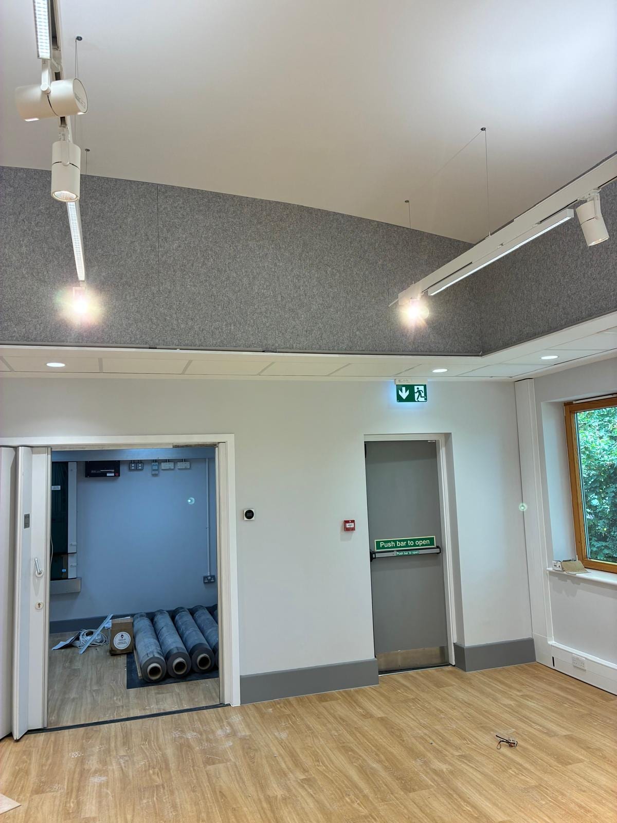 Acoustic ceiling curving over a doorway with green emergency exit signage