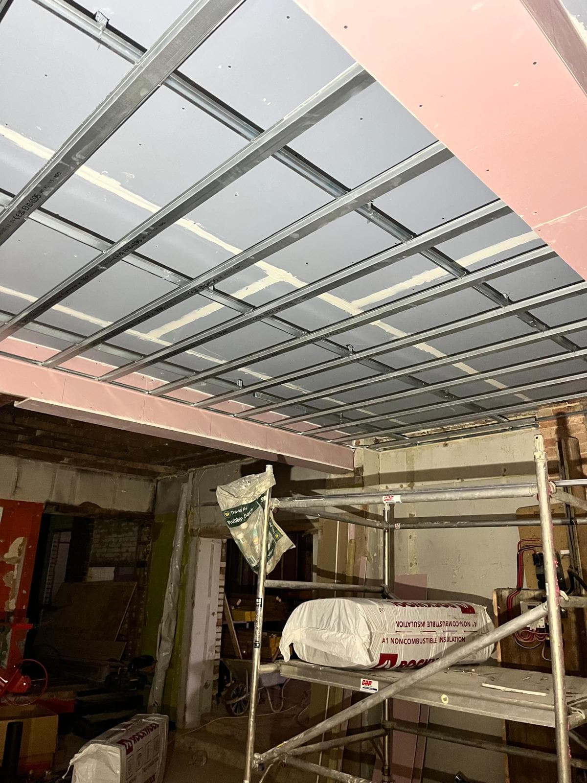 New suspended ceiling grid installed under the steelwork in the stripped out shop unit