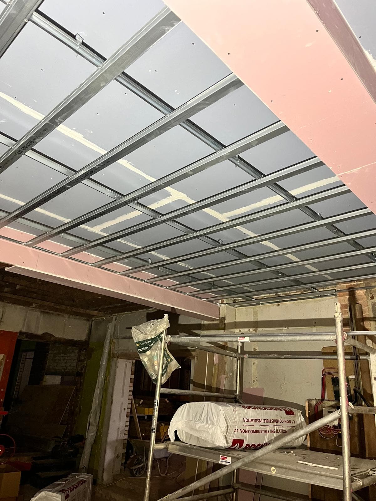 Suspended ceiling grid and primed steel beams across the shop floor