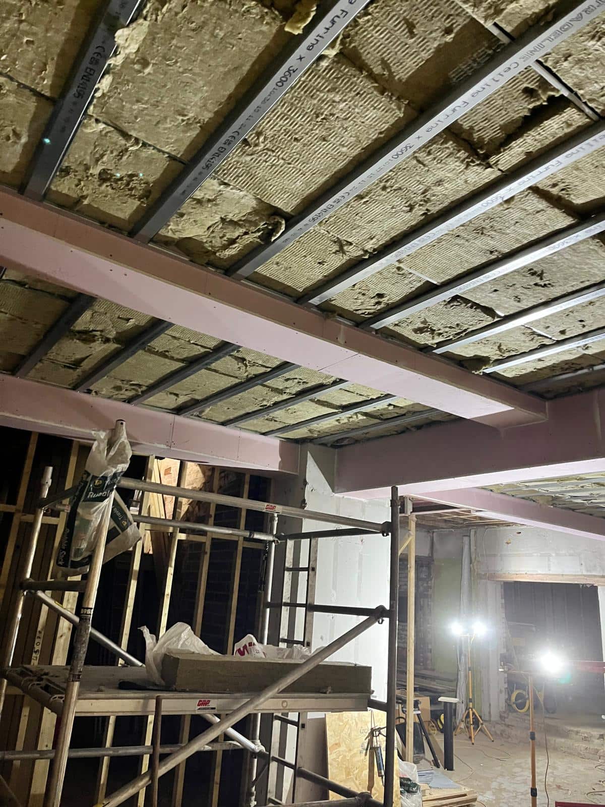 Old ceiling insulation being taken down between the new steel beams