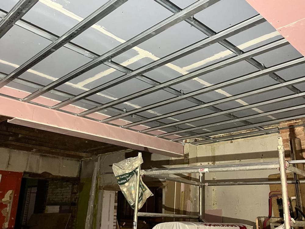 New suspended ceiling grid installed under the steelwork in the stripped out shop unit