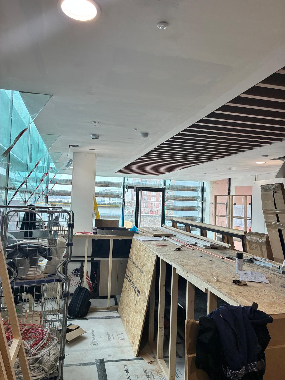Timber baffle ceiling and plastered bulkhead with the London street through the glazing