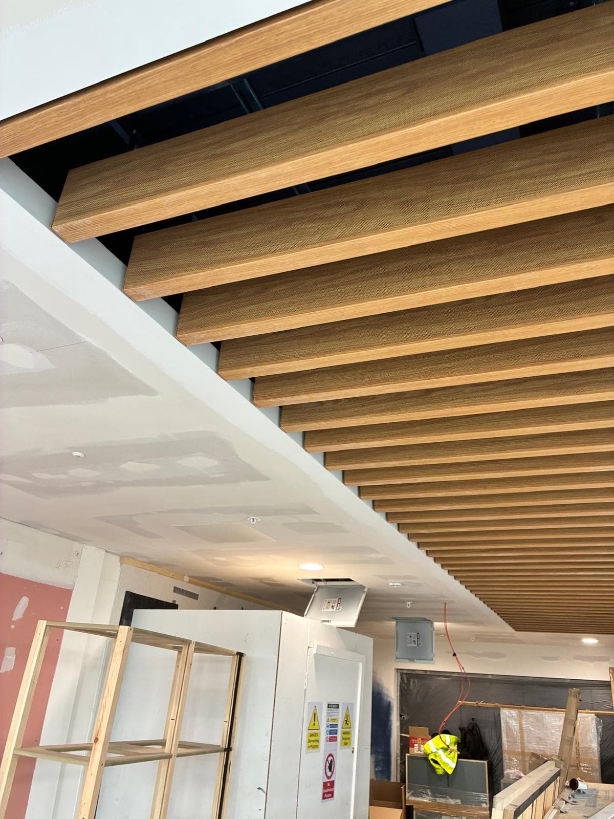 Close view of the timber baffle ceiling meeting the plastered bulkhead