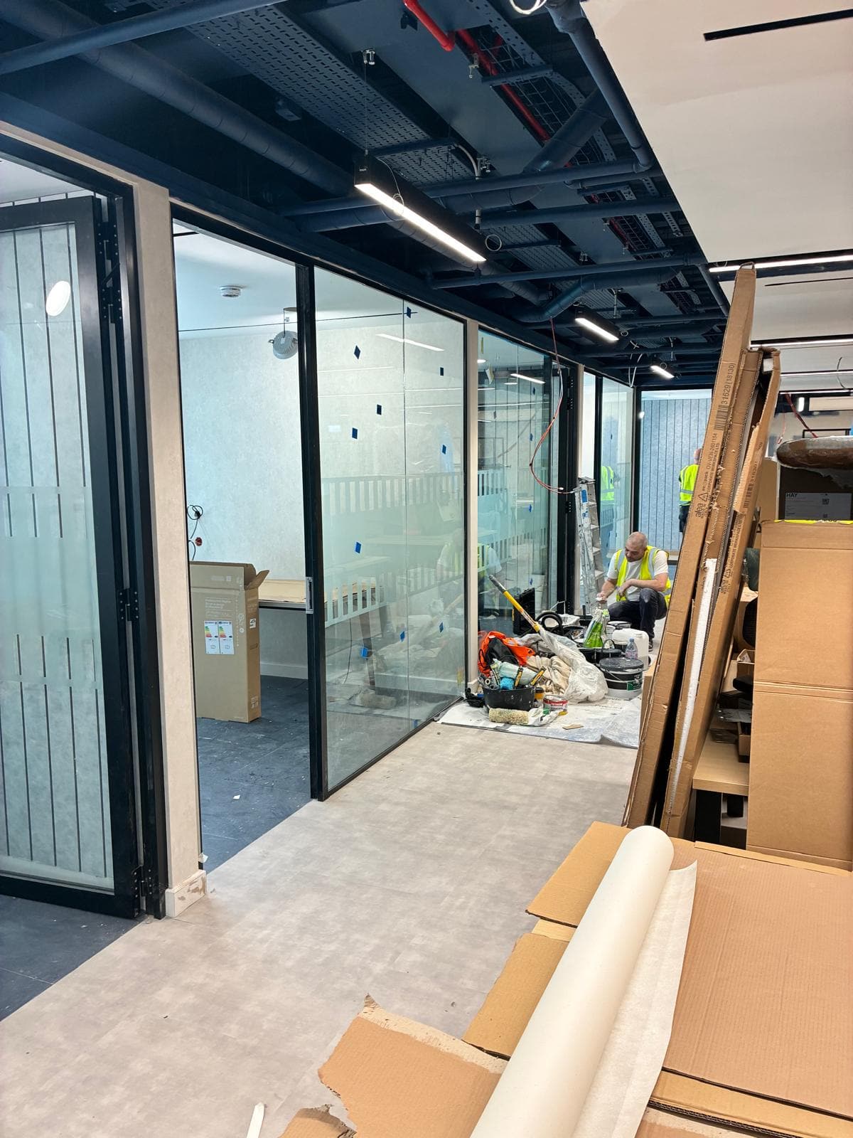 Glass partition offices with the ceiling services exposed and materials on site