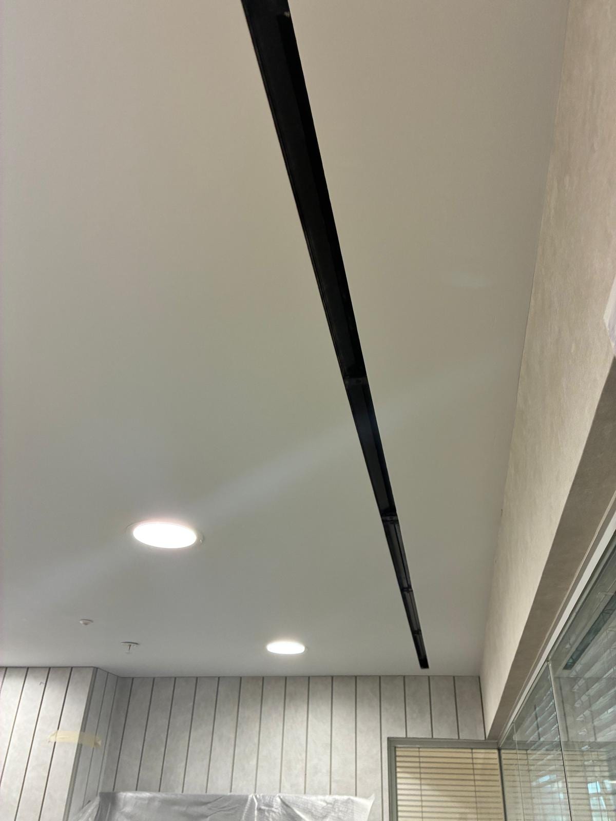 Plain plastered ceiling with a shadow gap and downlights above slatted wall panelling