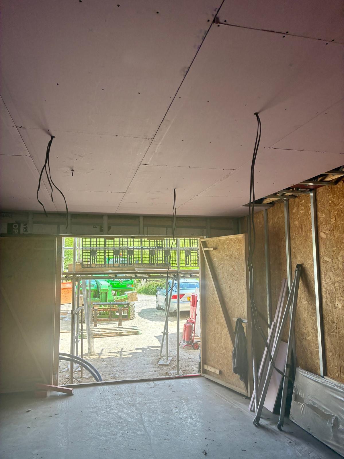 Plasterboard ceiling and metal stud partitions with the yard through the opening
