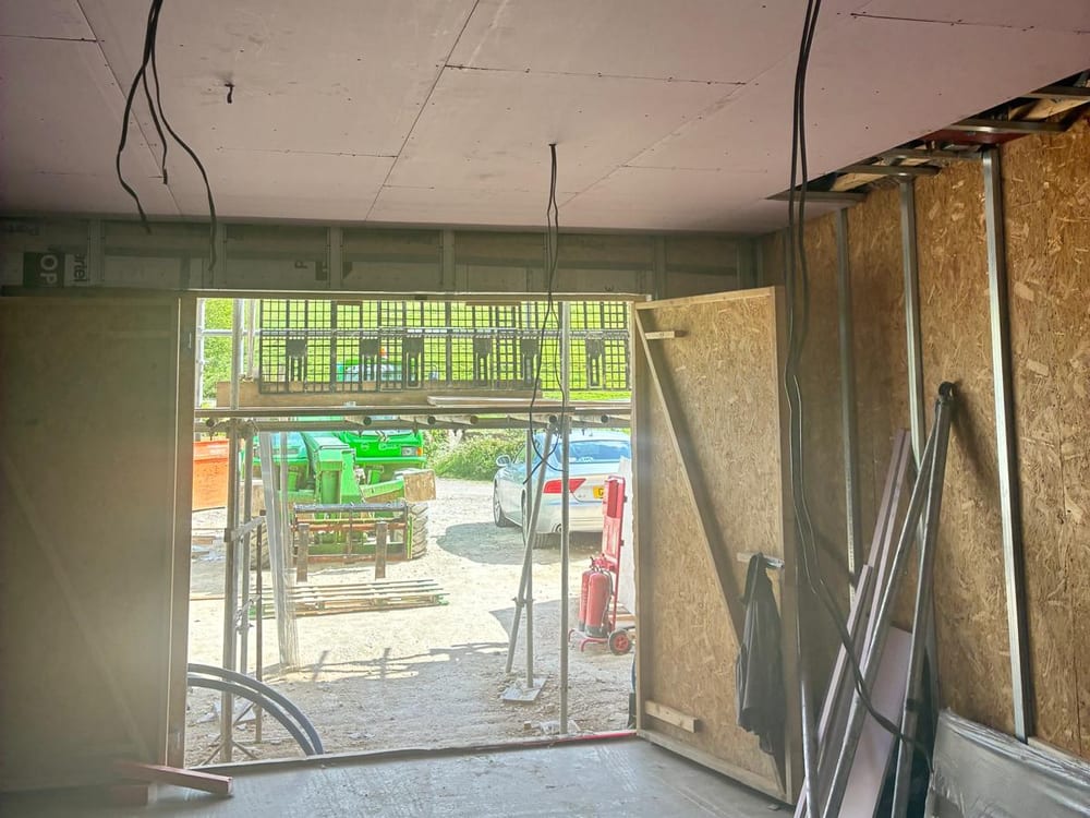 Plasterboard ceiling and metal stud partitions with the yard through the opening